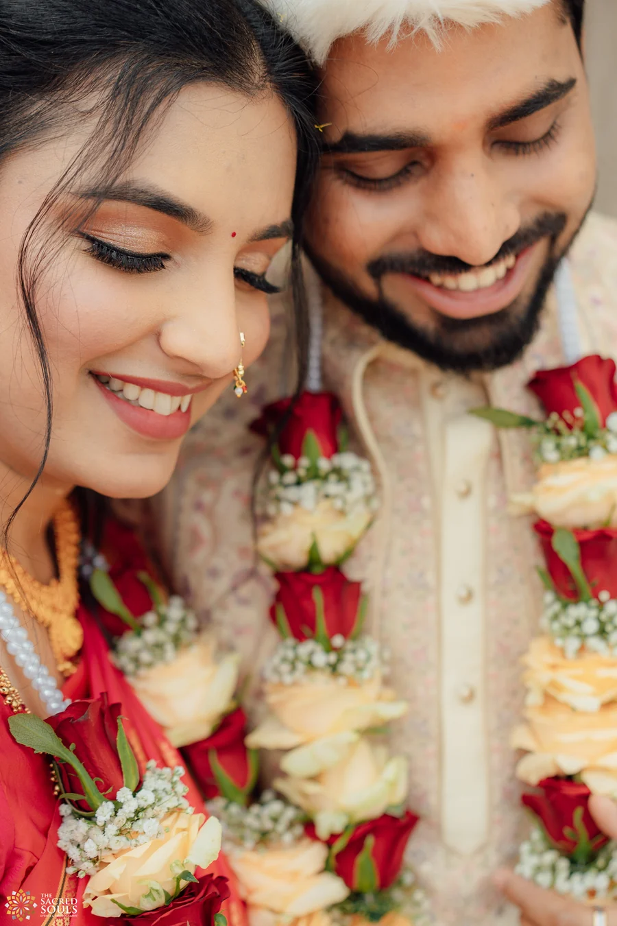 A bride and groom smiling close together in rose varmalas