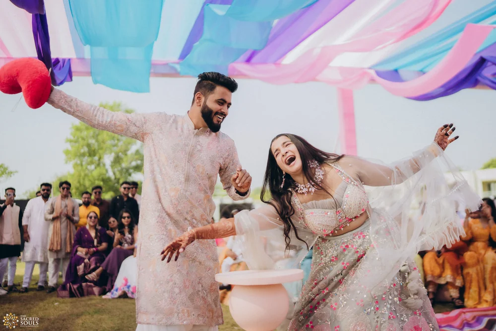 A bride and groom laughing under pastel streamers at their wedding