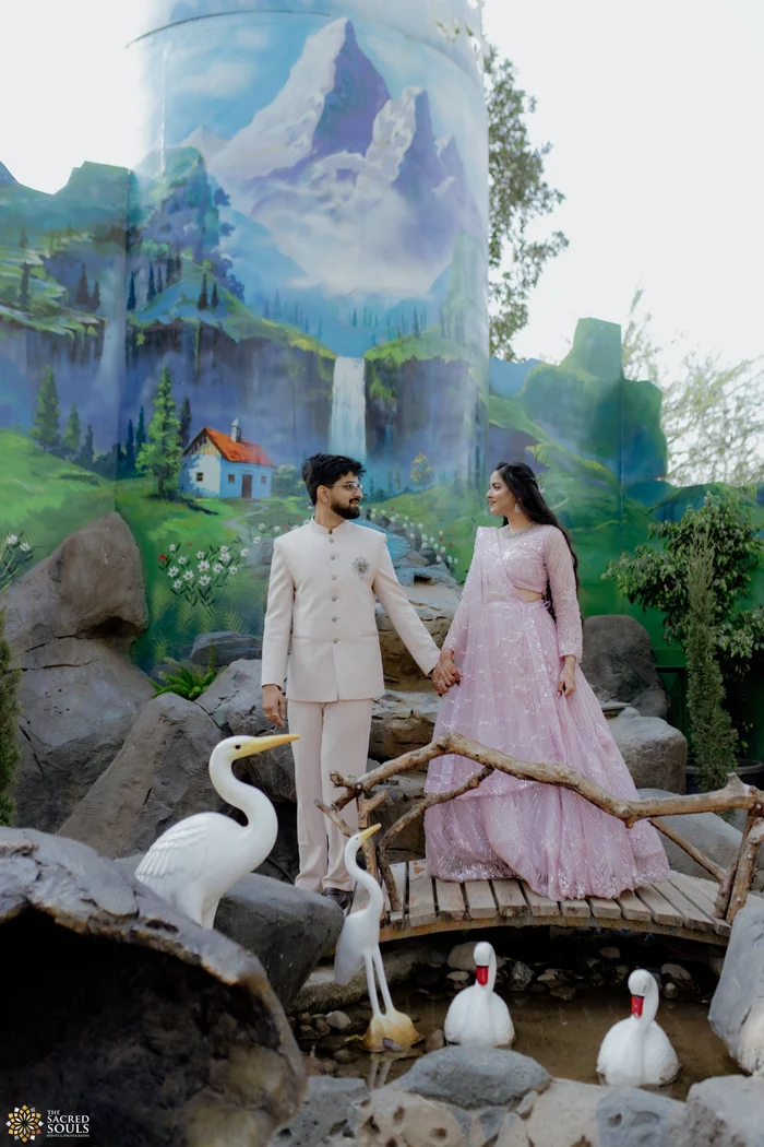 A couple in pastel outfits by a fountain with flamingo sculptures