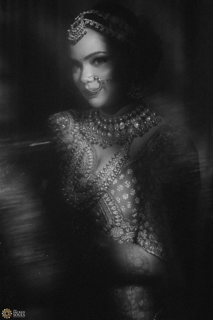 A black-and-white portrait of a bride in a jewelled dupatta