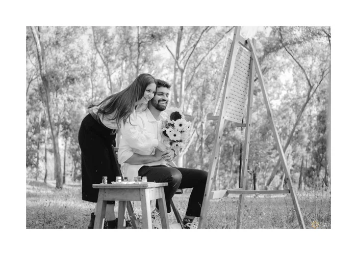 A black-and-white photo of a couple painting at an easel