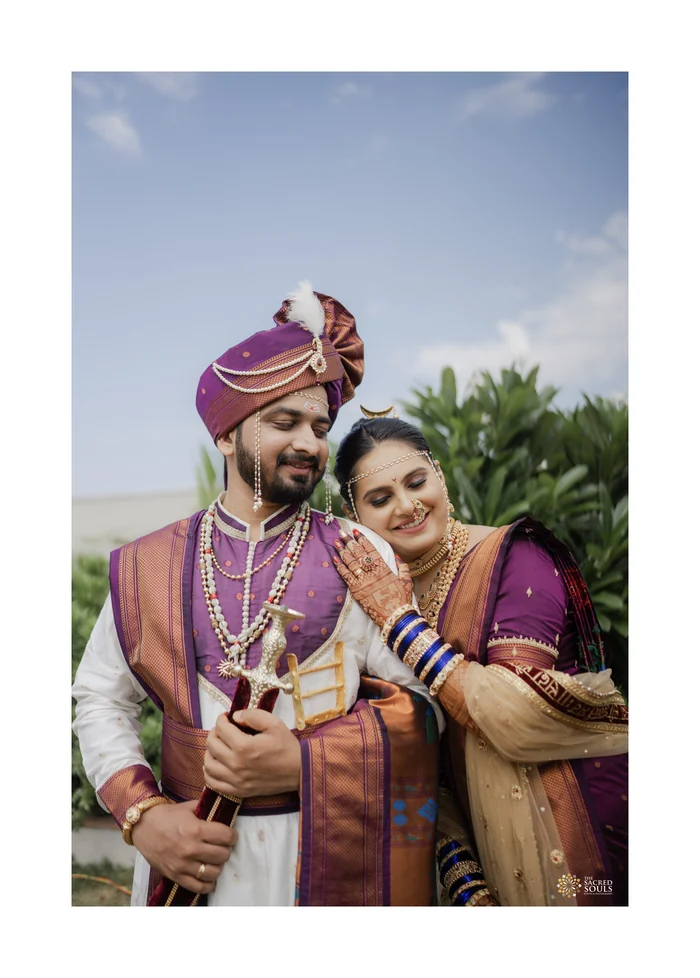 A couple in purple Paithani and pheta under a blue sky