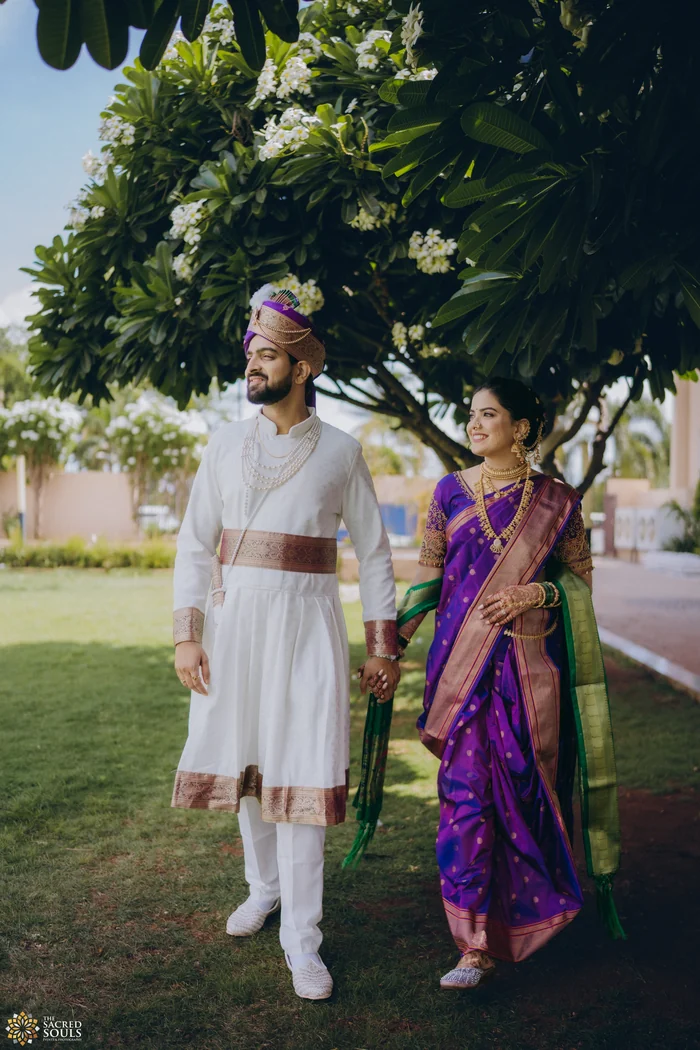 A bride and groom walking together under trees