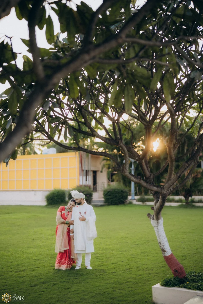 A couple standing on a lawn under a large tree