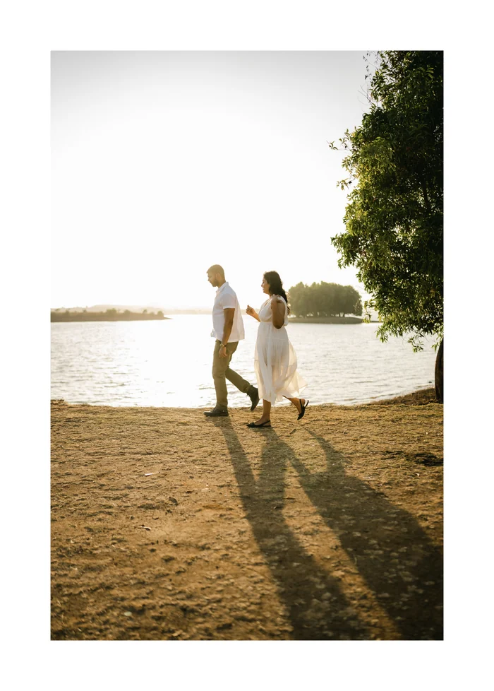A couple walking along a lake shore at sunset