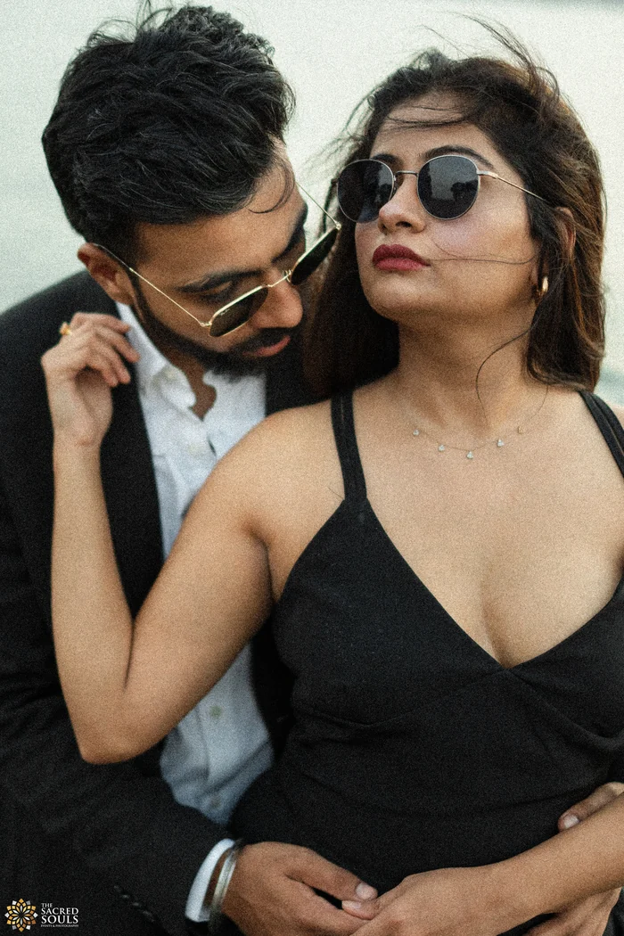 A couple in black, close together by the water