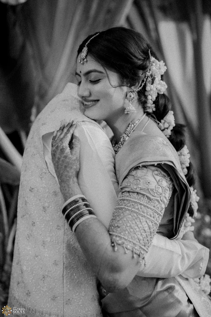 A black-and-white photo of a bride hugging her groom