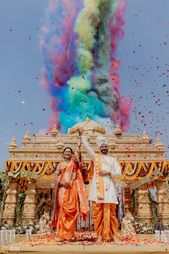 A bride and groom celebrating as coloured smoke bursts behind them