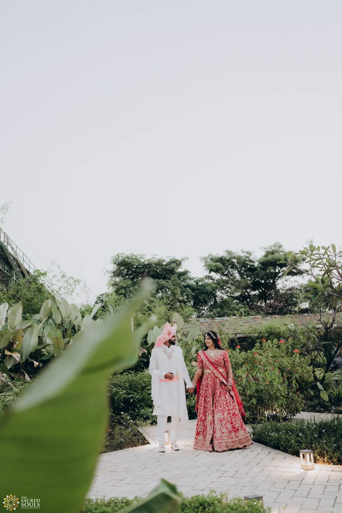 A couple walking hand in hand through a garden