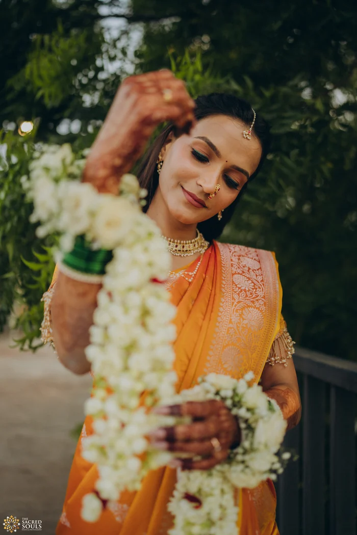 A bride laughing as she holds a jasmine garland