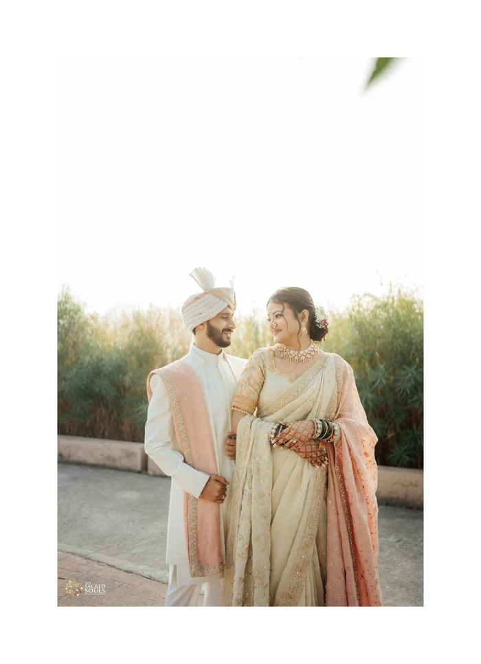 A couple in ivory outfits standing in a garden