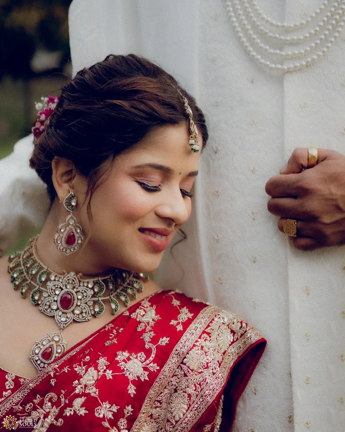 A bride in red smiling softly against her groom