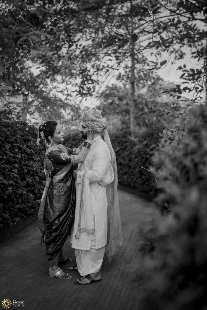 A black-and-white photo of a couple walking through trees