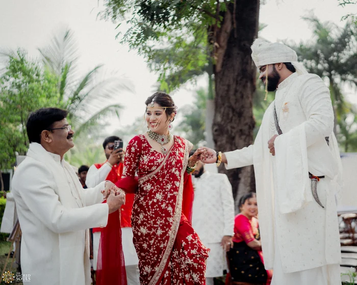 A bride in red being led by her family