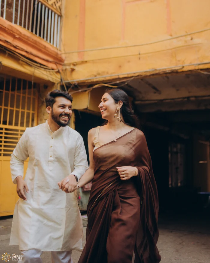 A couple walking past an old yellow building