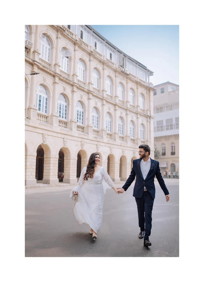 A couple walking past a grand old building in Mumbai