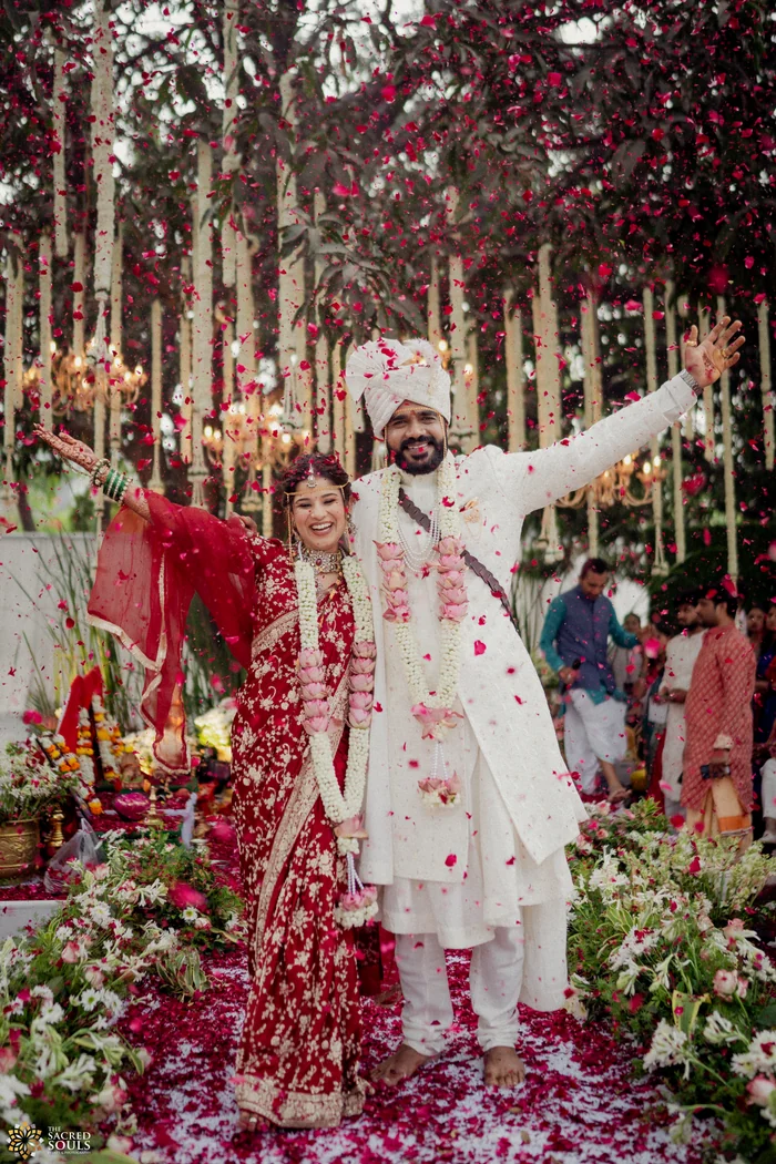 A groom raising his arms in celebration on a flower-covered stage