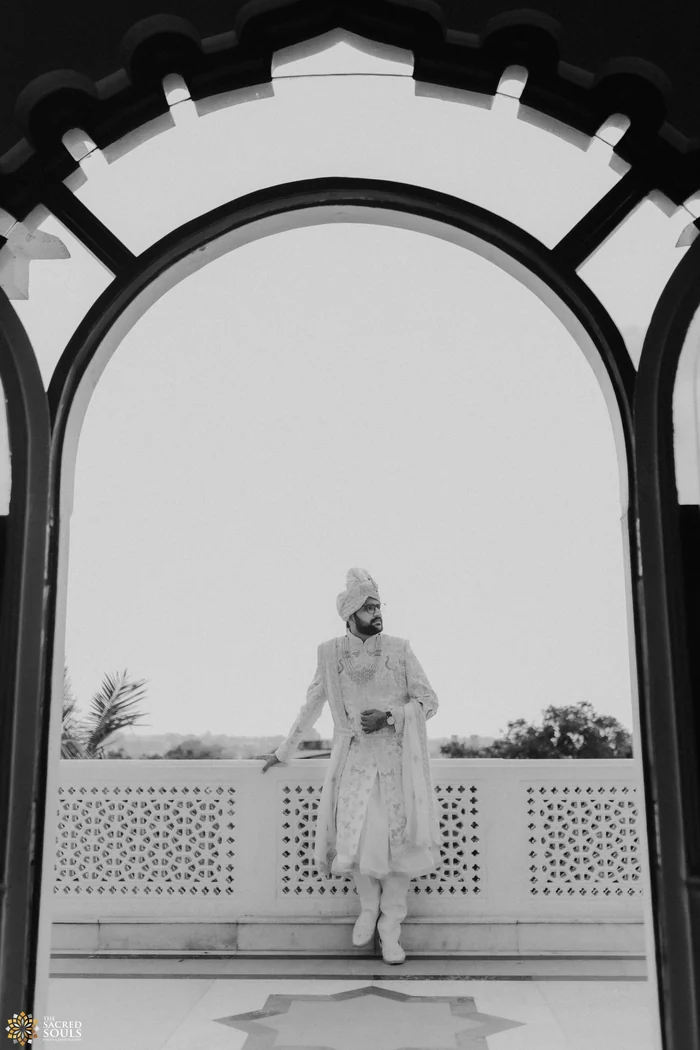 A groom framed by a white arch