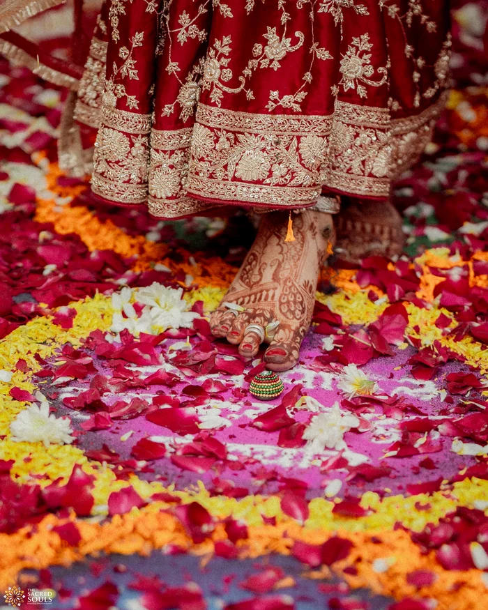 Close-up of a bride’s red lehenga on rose petals