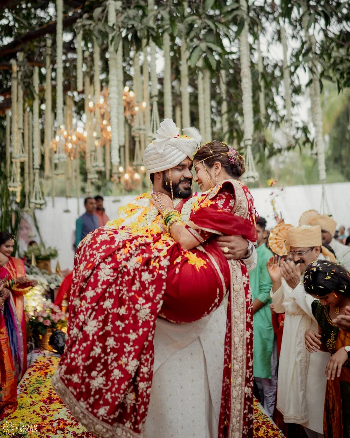 A bride and groom laughing under hanging flowers