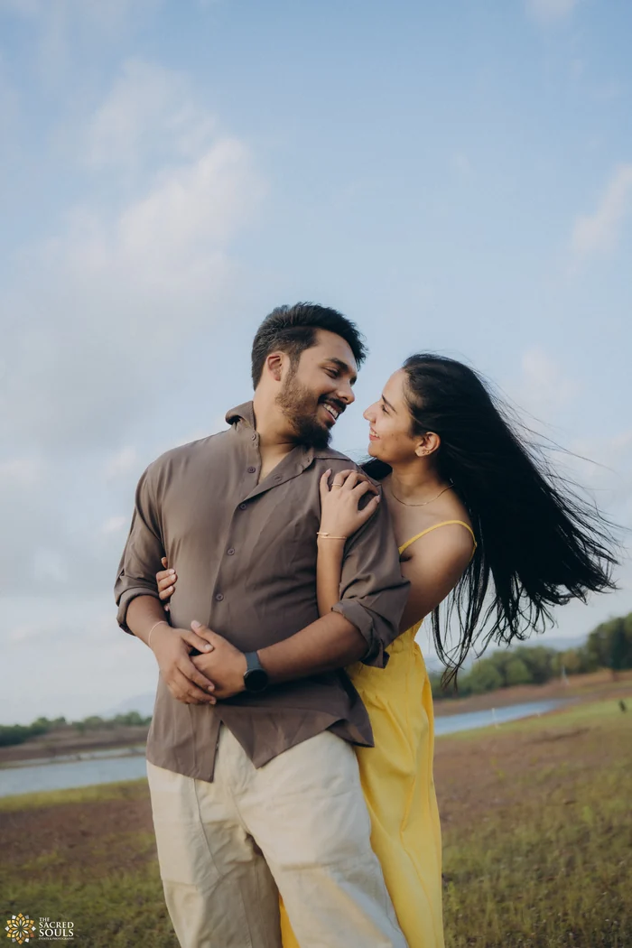 A couple laughing in a field by the water