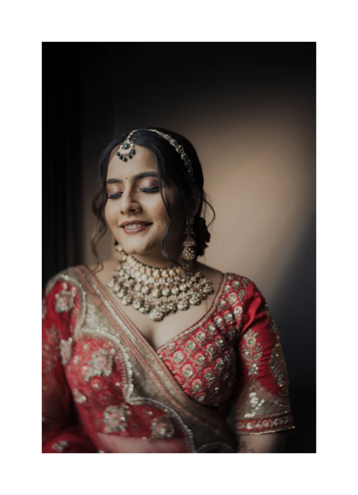 A bride in red jewellery smiling with her eyes closed