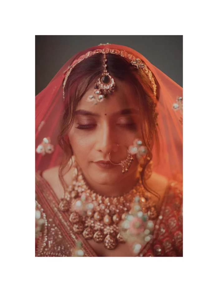 A bride looking down under a red veil