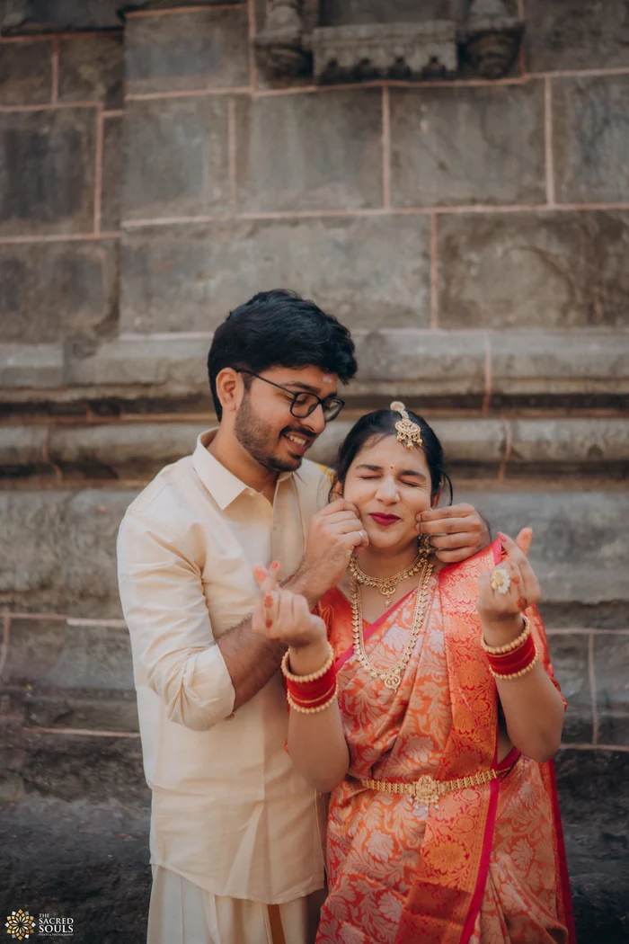 A couple smiling by an old stone wall