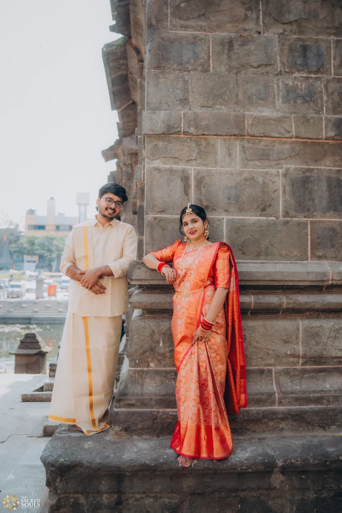 A couple standing by a stone pillar near the water