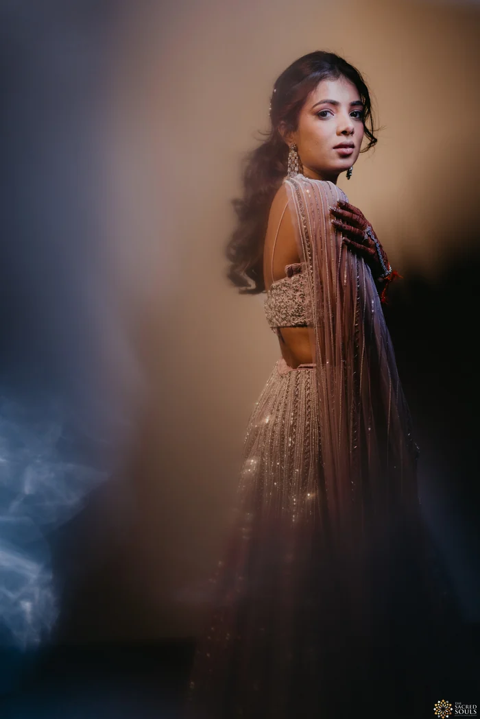 A bride in a shimmering outfit lit in blue and gold